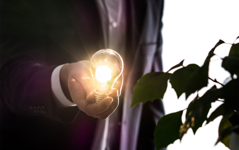 Businessman or man in a suit holding an illuminated light bulb in hand. Innovation, brainstorming and creativity concept. Environmental lawyer with an idea.